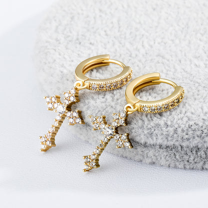 Gold hoop earrings with star-shaped pendants on a textured gray surface